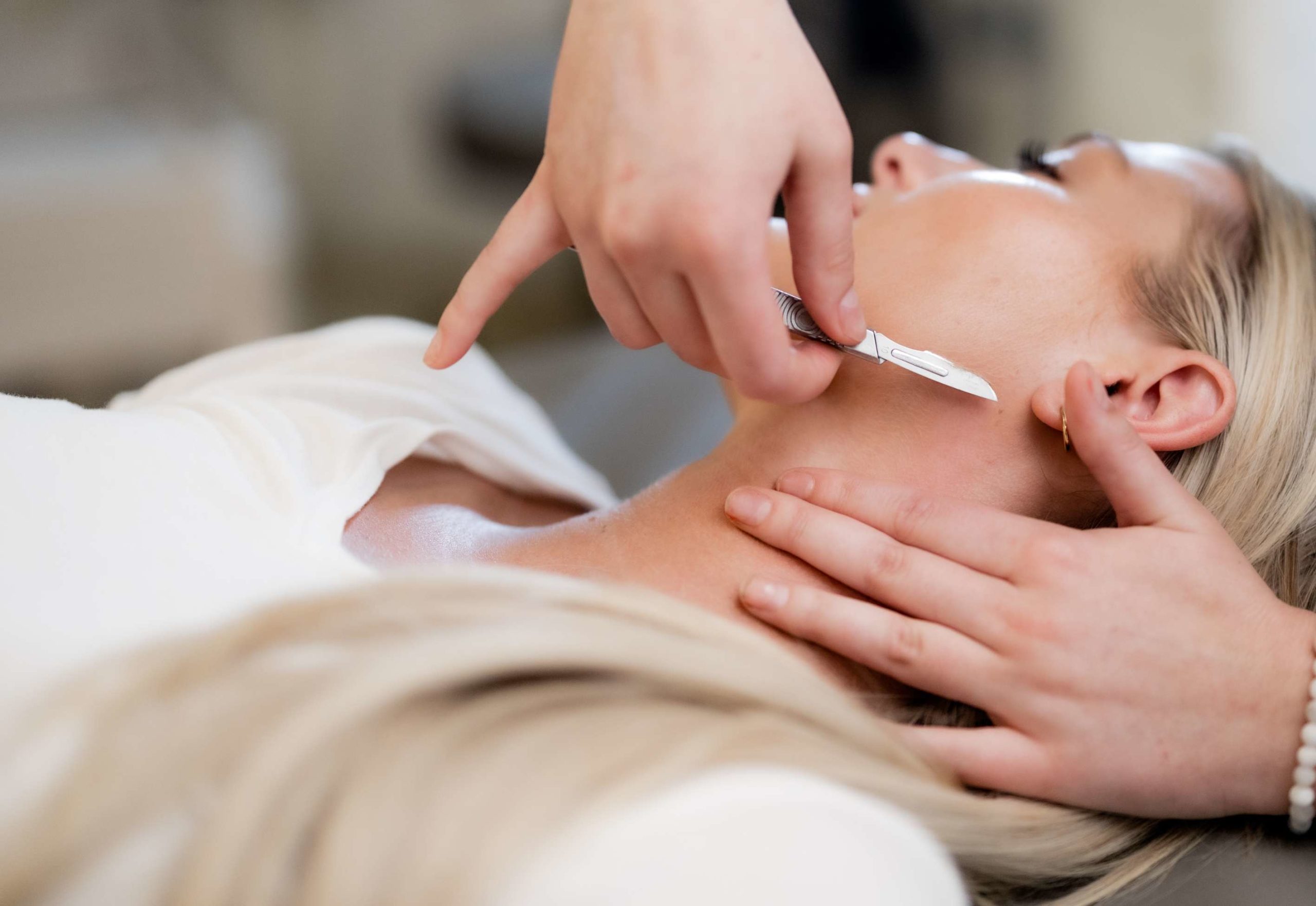 An esthetician giving her client a mini derma, or mini dermaplaning that the client used as an enhancement service.