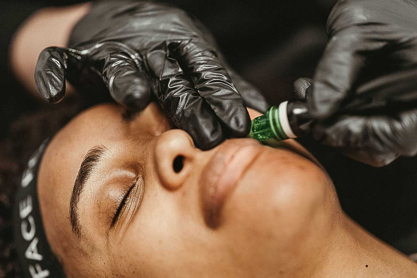 A woman receiving a Hydrafacial Service at a FACE FOUNDRIÉ facial bar from a skin expert.